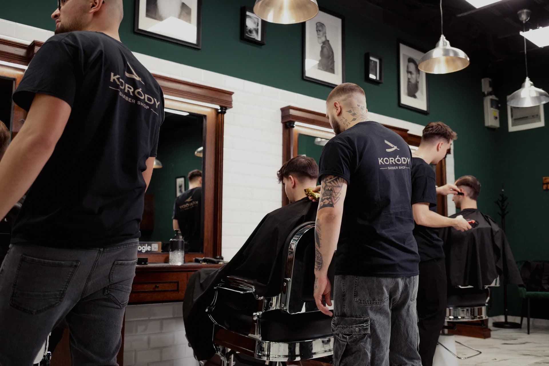 Barbers at work in Koródy Barber Shop's green-walled salon
